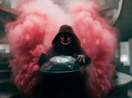 a man in a gas mask holding a helmet with smoke coming out of it