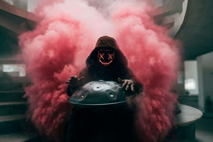 a man in a gas mask holding a helmet with smoke coming out of it